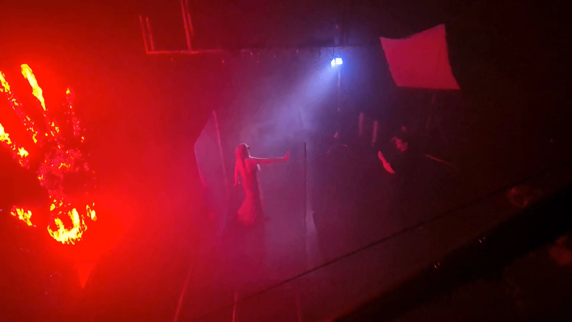 BTS: A shoot illuminated with red light, an artist with hands raised.
